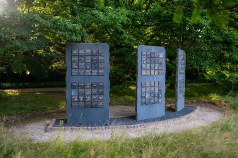 Twee rechtopstaande gedenkpanelen op een open plek tussen de bomen.