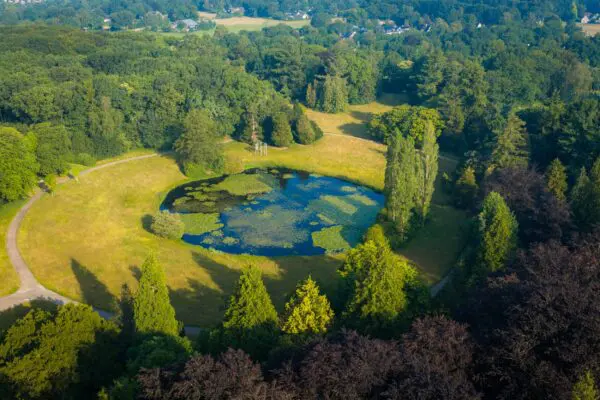 Luchtfoto van het groene terrein van Crematorium Kranenburg met waterpartijen en bomen.