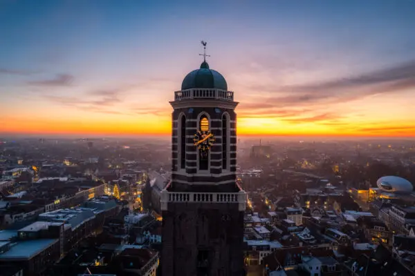 Uitzicht over Zwolle bij zonsondergang met een kerktoren op de voorgrond.